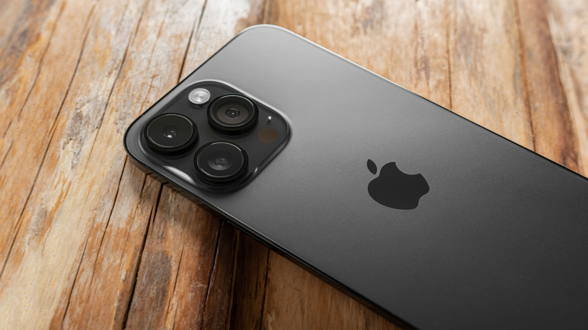 A gray iPhone 14 layng face down on a brown table