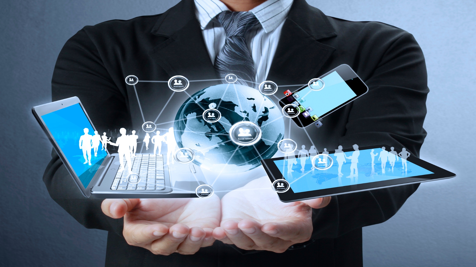 An image of a man holding a laptop, smartphone and tablet in a futuristic image.