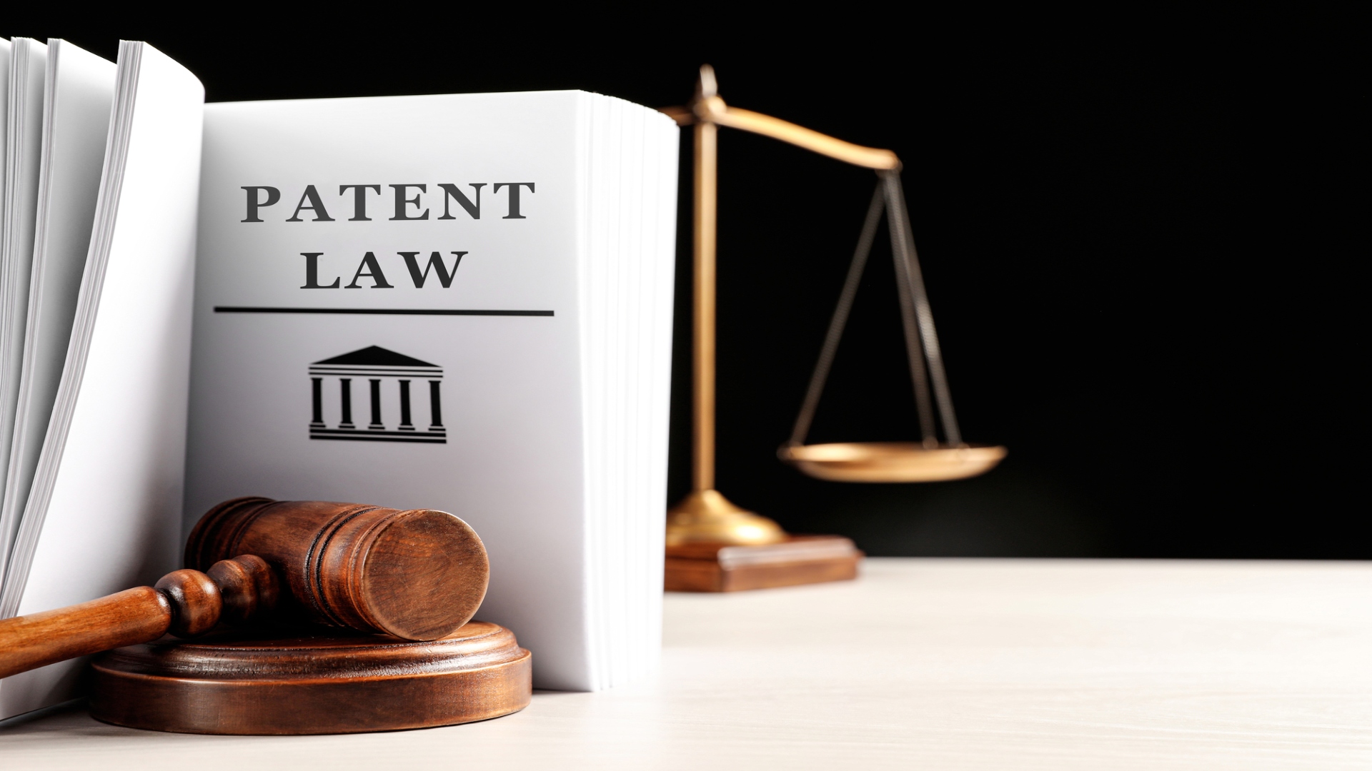 A gavel, patent law book and scales of justice on a table