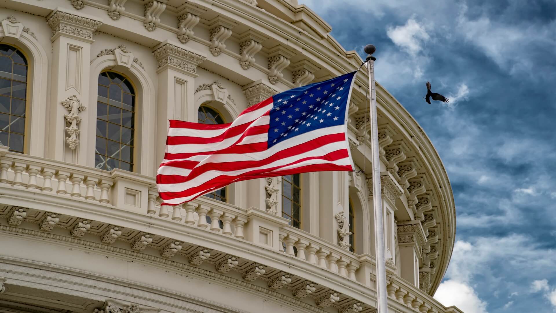 US Capitol building with United States flag blowing in front of the Capitol