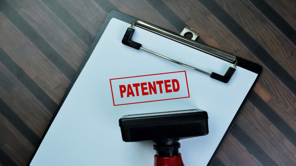 White clipboard with the word patented stamped on it next to the rubber stamp