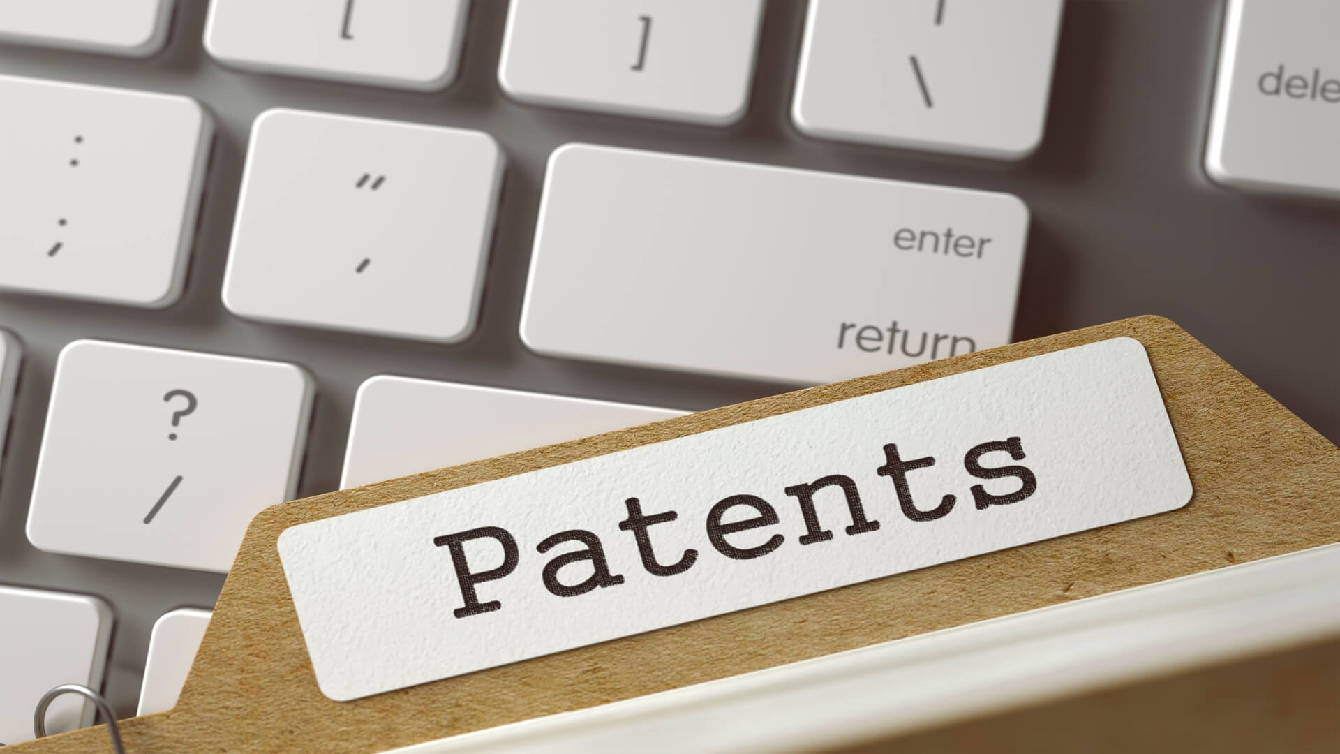 A file folder with a Patents label on top of a computer keyboard